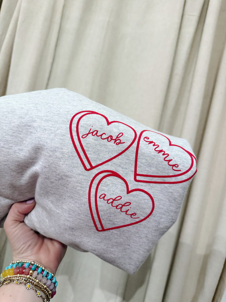 Gray sweatshirt with red heart-shaped names on a beige background