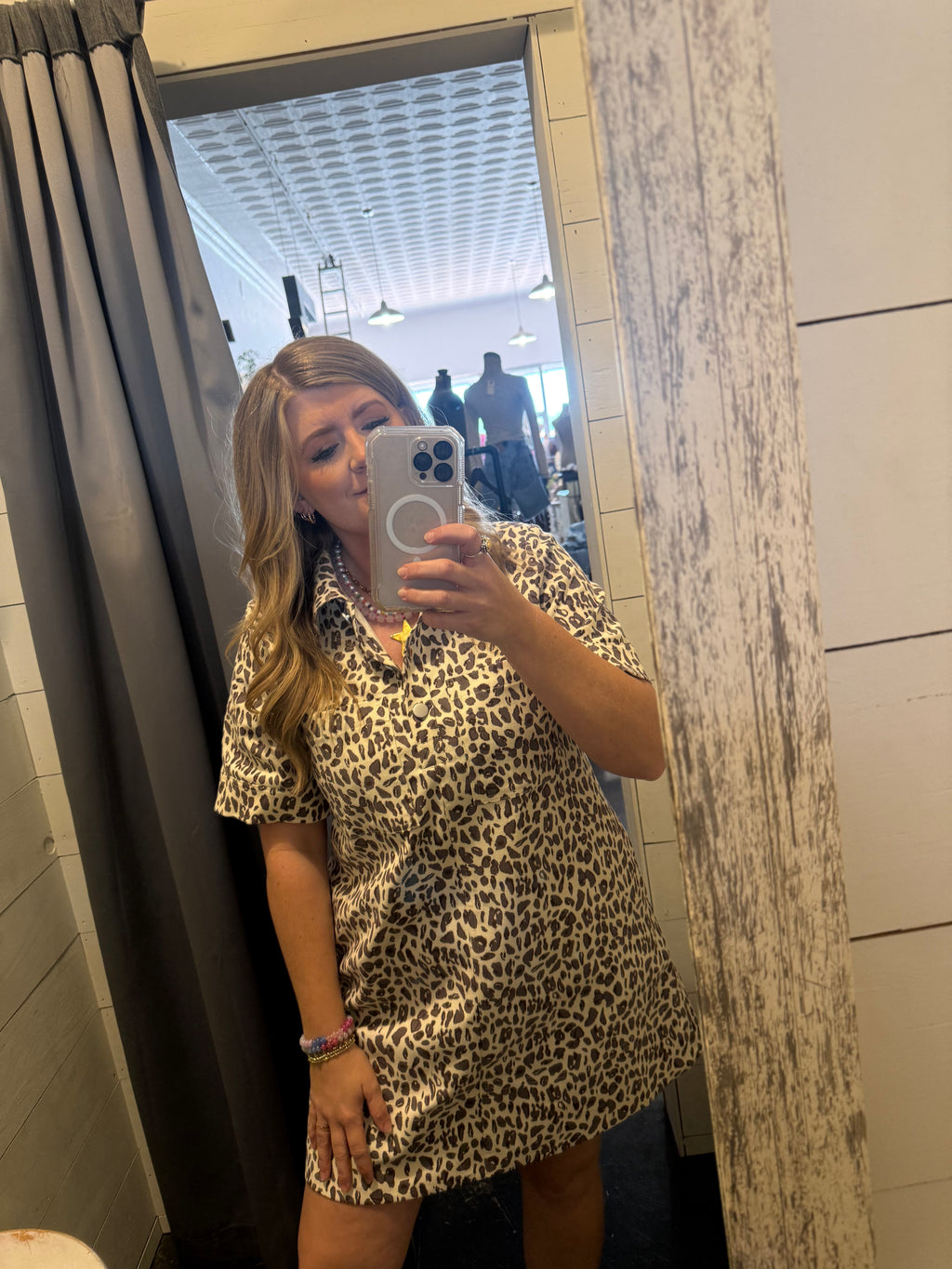 Person wearing a leopard print dress taking a mirror selfie.