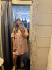 Person wearing a pink floral dress standing in front of a mirror.