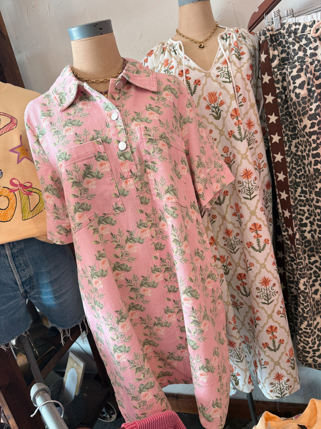 Floral patterned dresses and pants on a mannequin with graphic sweatshirt. Also leopard print fabric in the background.